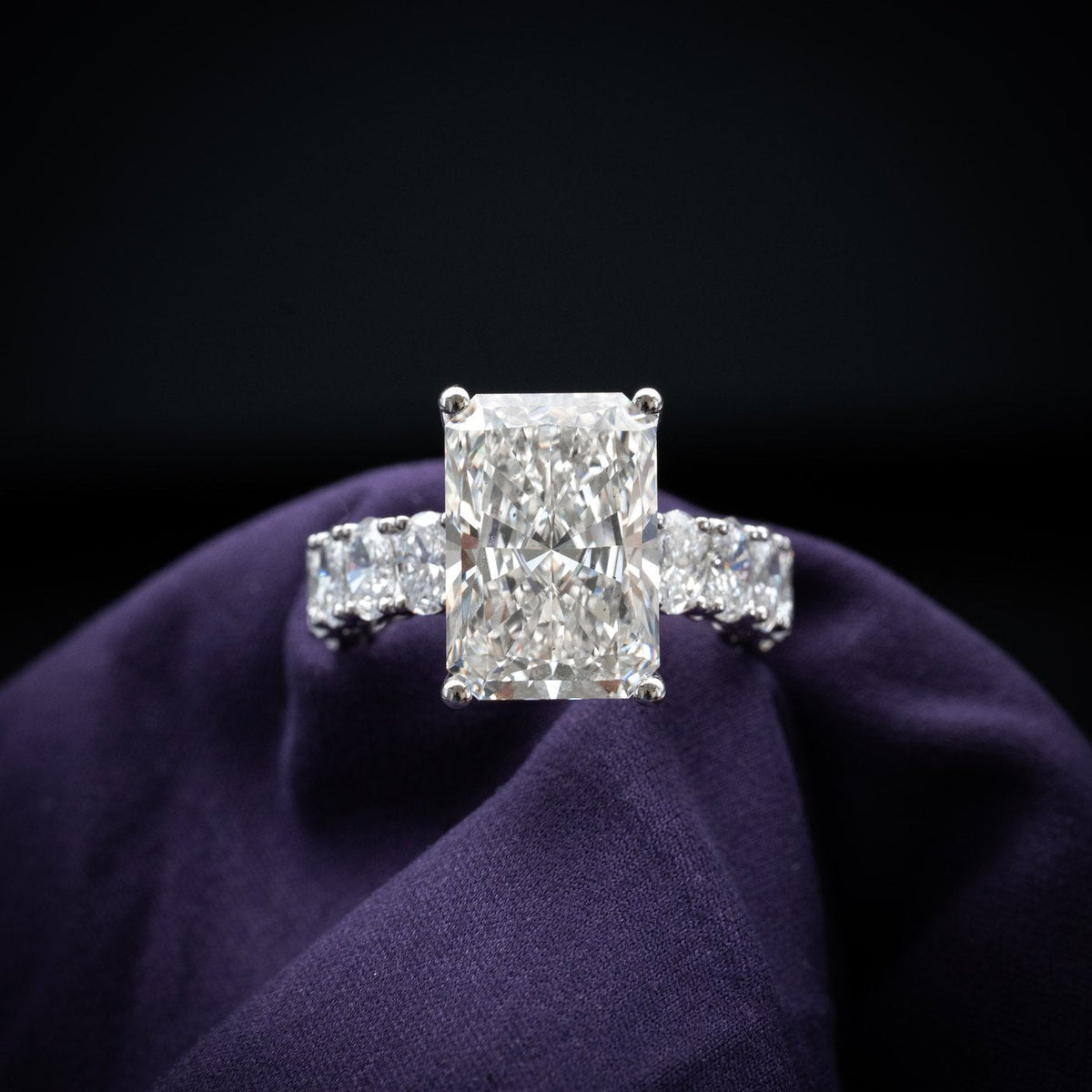 A radiant-cut solitaire engagement ring on an oval diamond band