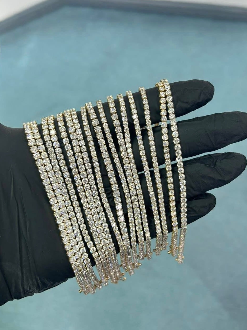 A gloved hand holding a row of diamond tennis bracelets.