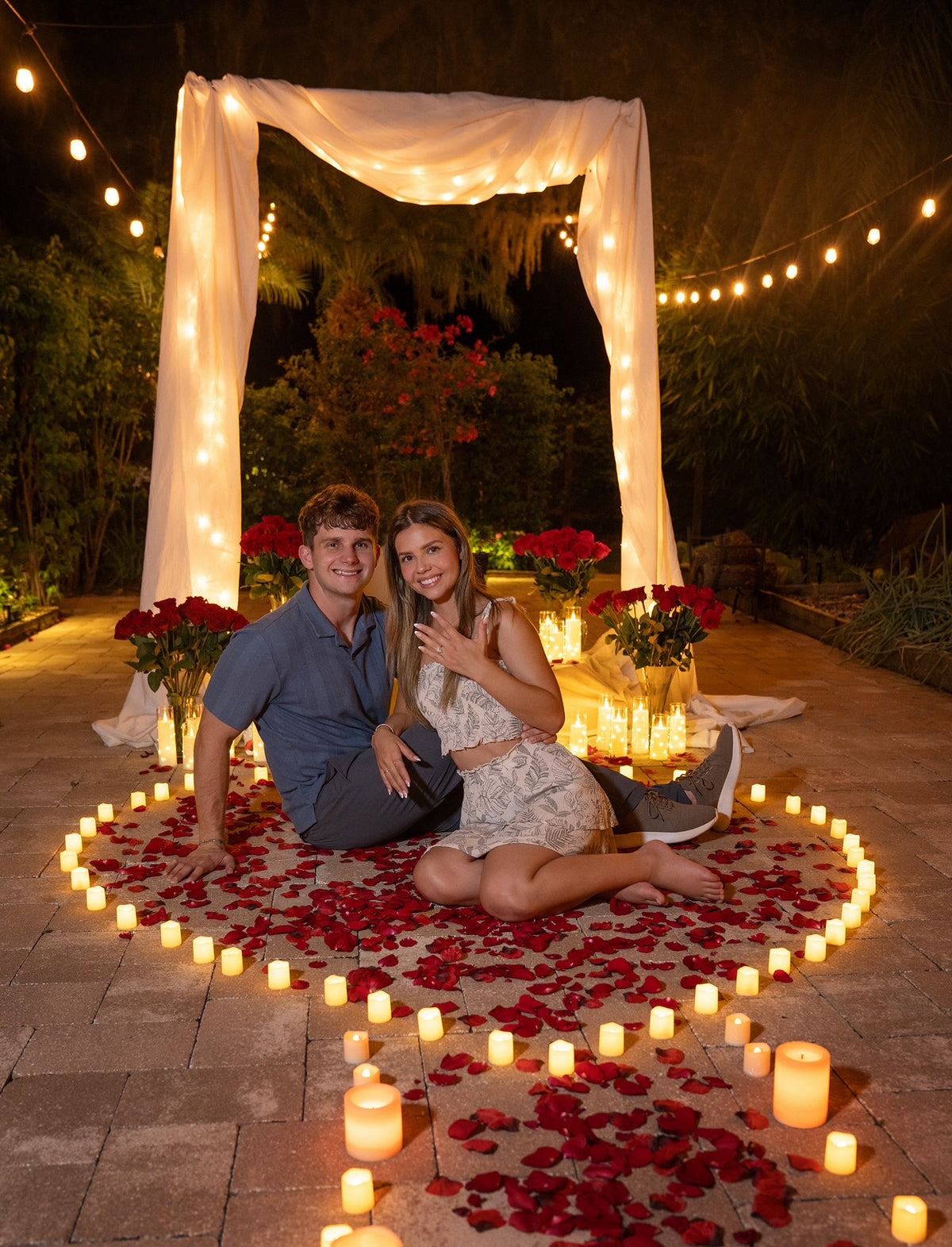 A couple after a candlelit proposal, the ring on her hand.