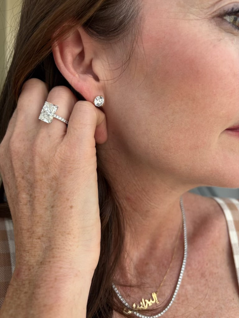 A diamond stud earring and radiant-cut diamond ring worn together.