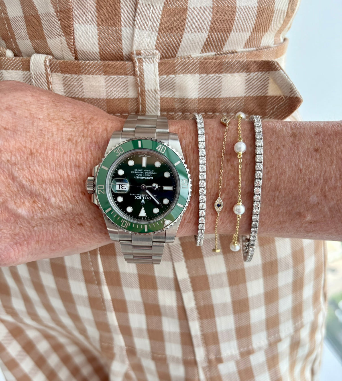 A Rolex Submariner worn alongside diamond tennis bracelets.